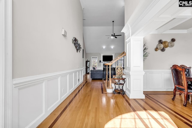 hall featuring decorative columns, light wood-style flooring, wainscoting, and stairway