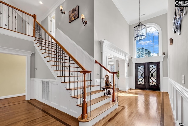 foyer with visible vents, crown molding, french doors, wood finished floors, and a notable chandelier