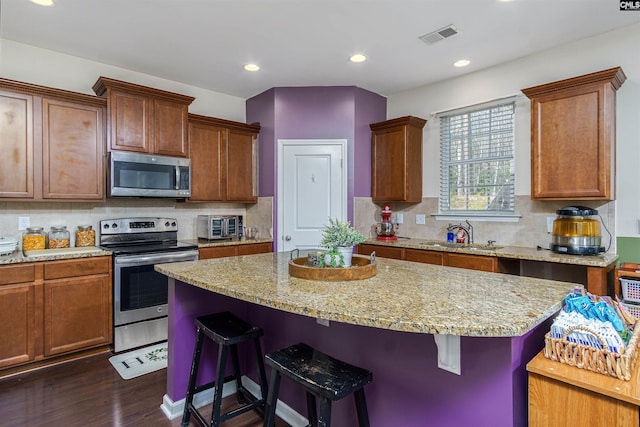 kitchen with dark wood-style flooring, a breakfast bar area, stainless steel appliances, and a sink