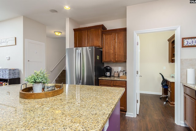 kitchen with dark wood finished floors, light stone counters, decorative backsplash, freestanding refrigerator, and built in study area