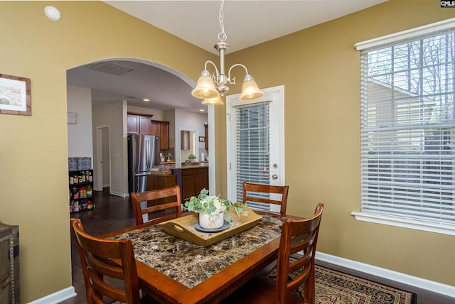 dining area featuring visible vents, baseboards, a chandelier, arched walkways, and dark wood-style flooring