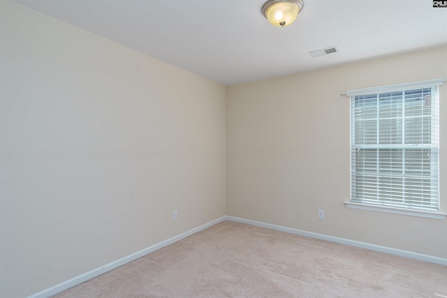 spare room featuring visible vents, light carpet, and baseboards