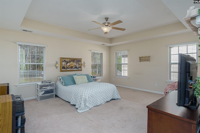 bedroom with baseboards, visible vents, ceiling fan, a raised ceiling, and carpet flooring