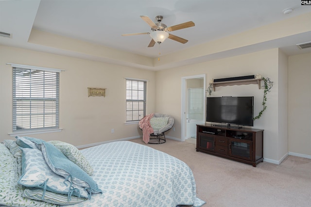 bedroom featuring visible vents, light colored carpet, baseboards, and a tray ceiling