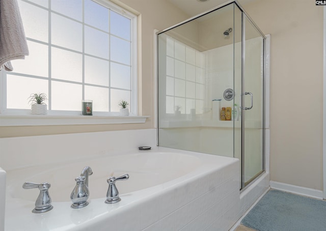 full bath featuring a wealth of natural light, baseboards, a stall shower, and a bath