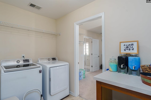 clothes washing area with visible vents, light colored carpet, laundry area, and washing machine and clothes dryer