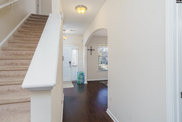 entryway with visible vents, baseboards, arched walkways, stairs, and dark wood-type flooring