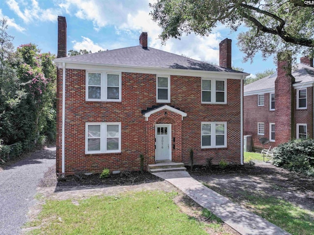 view of front facade with brick siding and a chimney