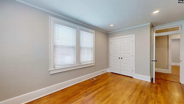 unfurnished bedroom featuring visible vents, baseboards, light wood-type flooring, ornamental molding, and a closet