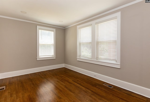 unfurnished room featuring dark wood finished floors, crown molding, baseboards, and visible vents