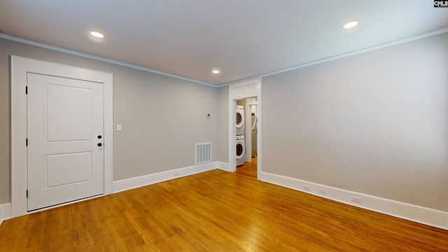 unfurnished room with visible vents, light wood-style flooring, recessed lighting, ornamental molding, and stacked washer and dryer