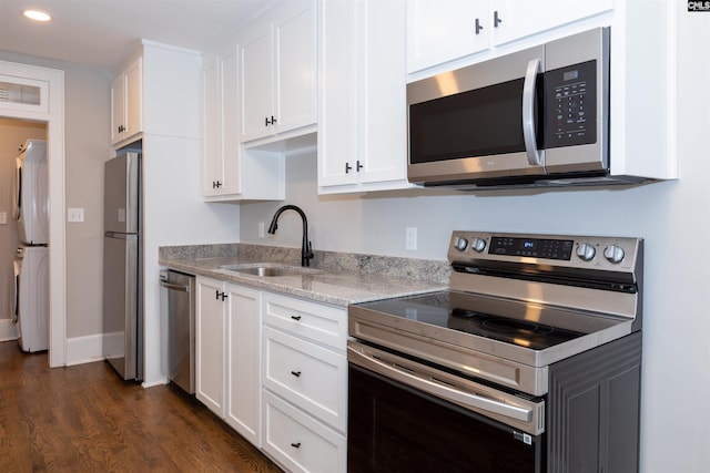 kitchen featuring a sink, light stone counters, white cabinetry, stainless steel appliances, and dark wood-style flooring