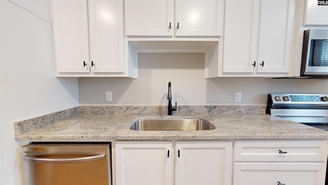 kitchen with a sink, light stone counters, white cabinetry, and stainless steel appliances