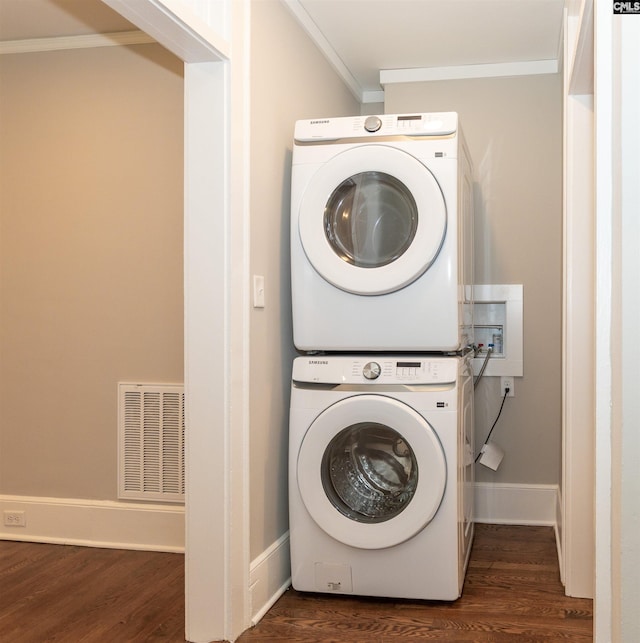 clothes washing area featuring dark wood-style floors, visible vents, laundry area, ornamental molding, and stacked washer / dryer