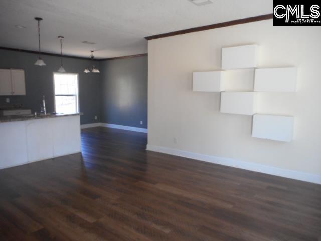 unfurnished living room with dark wood-style floors, baseboards, a chandelier, and ornamental molding