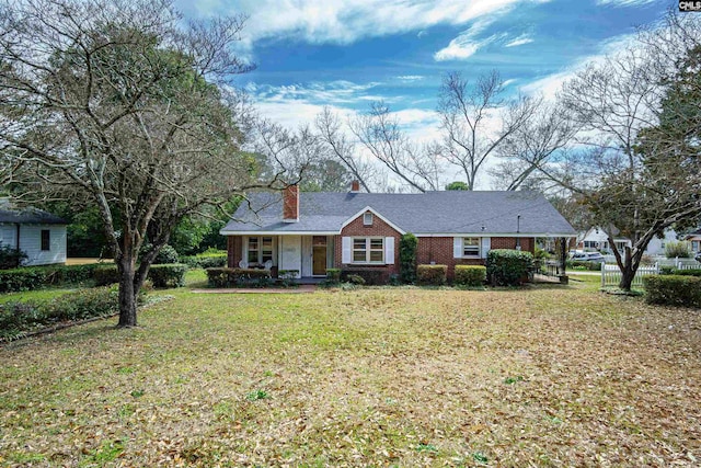 ranch-style house with brick siding, a chimney, a front lawn, and fence