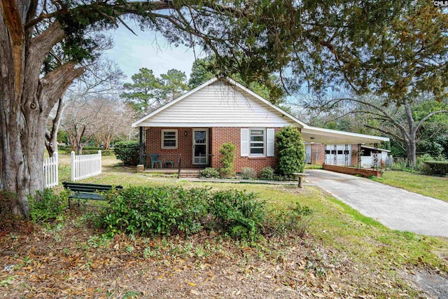 view of front of house with a front yard, fence, driveway, a carport, and brick siding