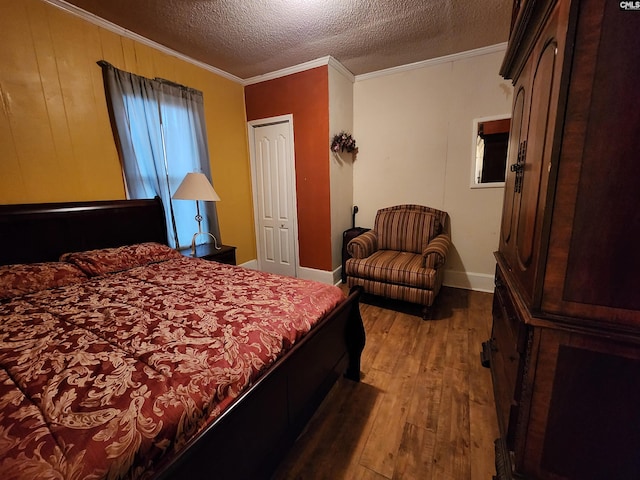 bedroom featuring a textured ceiling, wood finished floors, baseboards, and ornamental molding