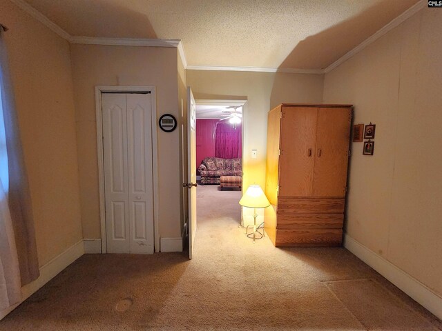 hall featuring a textured ceiling, baseboards, carpet floors, and ornamental molding