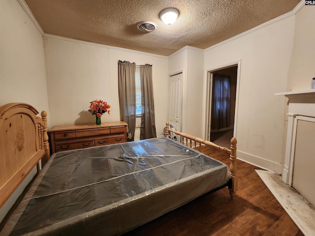 bedroom featuring wood finished floors, visible vents, a fireplace, ornamental molding, and a textured ceiling