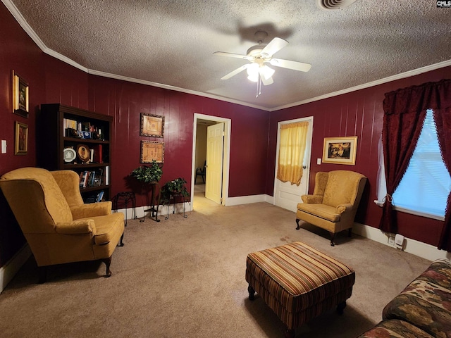 sitting room featuring carpet floors, a textured ceiling, ornamental molding, and a ceiling fan