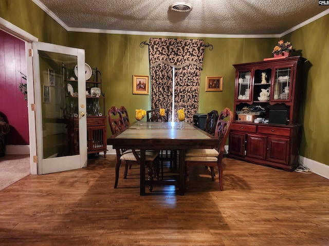 dining space with crown molding, wood finished floors, visible vents, and a textured ceiling