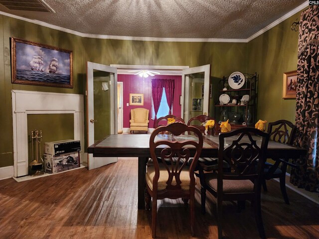 dining room with a textured ceiling, wood finished floors, visible vents, and ornamental molding