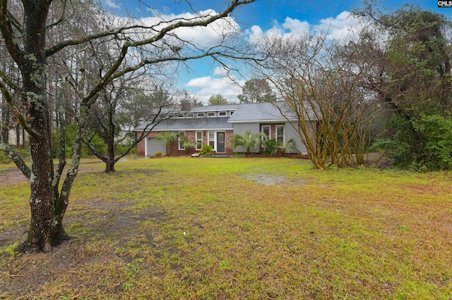 mid-century home featuring a front yard, brick siding, a garage, and driveway