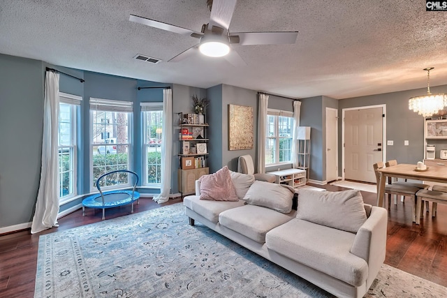 living area featuring visible vents, baseboards, ceiling fan with notable chandelier, wood finished floors, and a textured ceiling