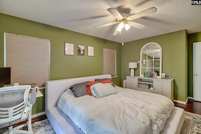 bedroom with baseboards, a textured ceiling, wood finished floors, and a ceiling fan