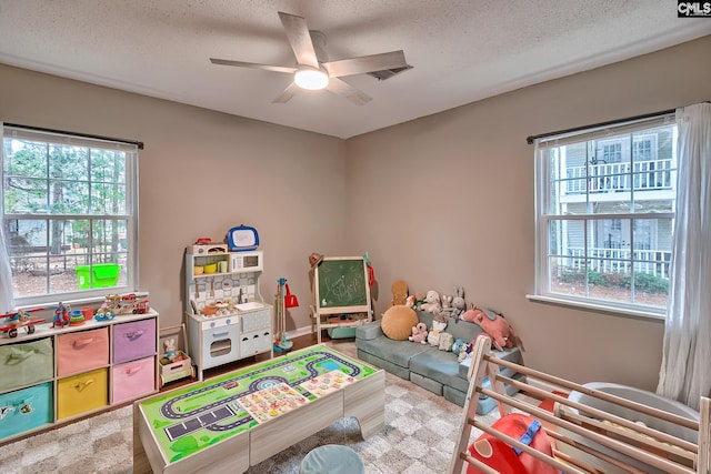 recreation room with a textured ceiling and a ceiling fan