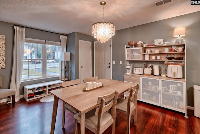 dining area with baseboards, visible vents, an inviting chandelier, dark wood-type flooring, and a textured ceiling