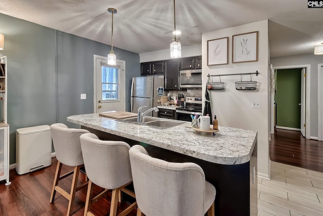 kitchen featuring appliances with stainless steel finishes, a breakfast bar area, light countertops, and a sink