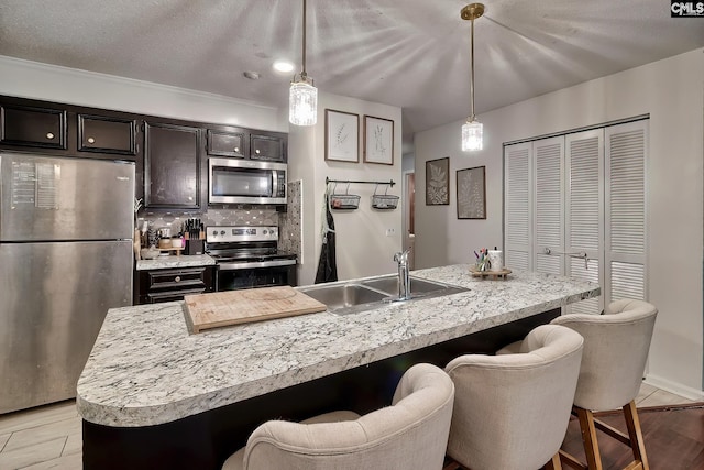 kitchen featuring a breakfast bar area, a sink, stainless steel appliances, light countertops, and tasteful backsplash