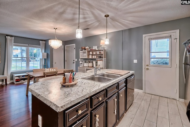 kitchen with visible vents, a sink, light wood finished floors, dishwasher, and light countertops