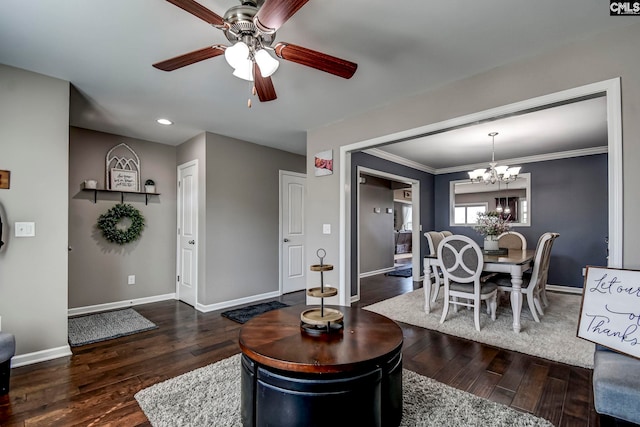 living room featuring ceiling fan with notable chandelier, hardwood / wood-style flooring, crown molding, and baseboards