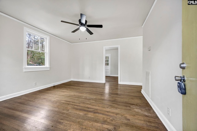 spare room featuring visible vents, dark wood-type flooring, ornamental molding, baseboards, and ceiling fan