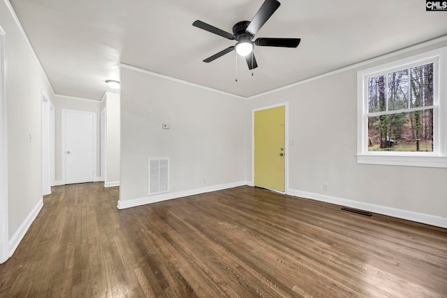 empty room featuring visible vents, crown molding, baseboards, and wood finished floors