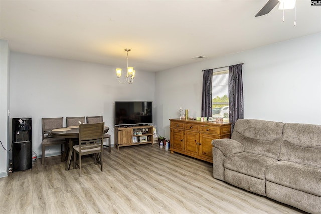 living area with visible vents, light wood-style flooring, and ceiling fan with notable chandelier