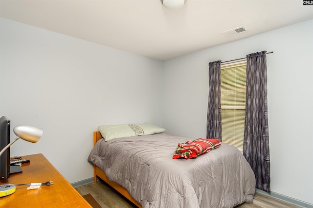 bedroom featuring visible vents, baseboards, and wood finished floors