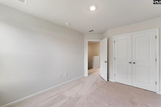 unfurnished bedroom with light carpet, a closet, baseboards, and visible vents