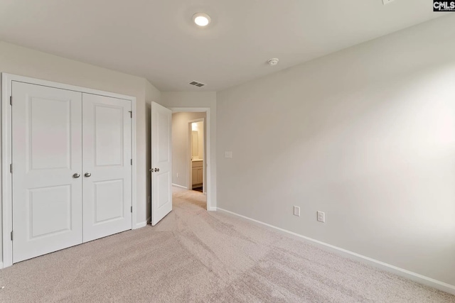 unfurnished bedroom with visible vents, baseboards, a closet, and light carpet