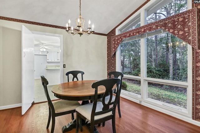 dining area with vaulted ceiling, ceiling fan with notable chandelier, baseboards, and wood finished floors