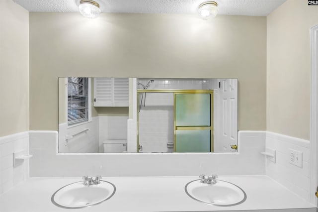 full bathroom with a sink, a textured ceiling, and a shower stall