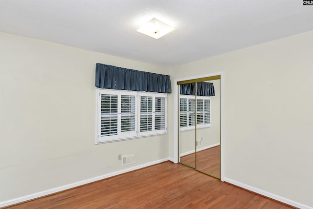 spare room with visible vents, wood finished floors, baseboards, and a textured ceiling