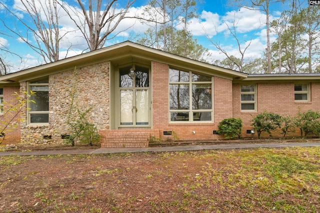 view of side of home featuring crawl space and brick siding