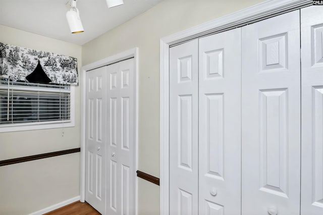 interior space featuring baseboards, multiple closets, and wood finished floors