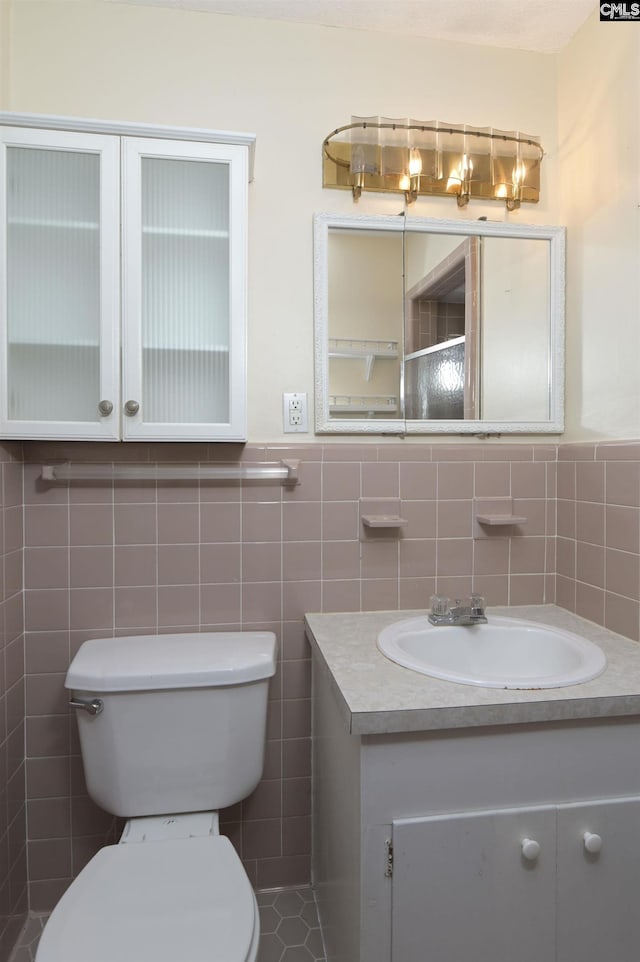 bathroom with a wainscoted wall, toilet, tile walls, and vanity