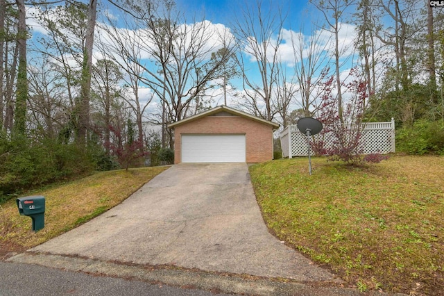 view of front of home with a front yard, an outbuilding, brick siding, and a detached garage