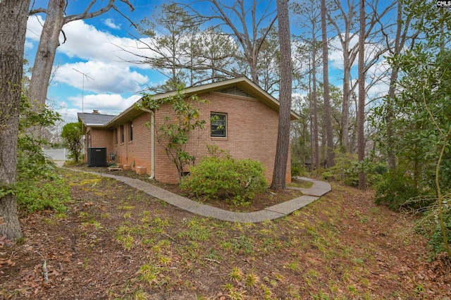 view of side of home with brick siding and central AC